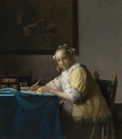 A lady in yellow writing a letter.